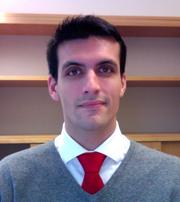 Iñigo Alonso at the office, wearing grey sweater and red tie.